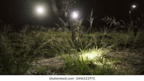 Detective, search party and flashlight at night in field, missing person and investigation of police. Crime scene, outdoor and tactical team to patrol in dark and coordination of emergency response