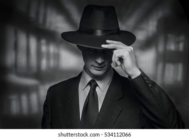 The detective takes on the camera. Vintage style black and white image of a polite young man in a suit doffing his hat in acknowledgement or greeting