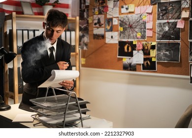 Detective working at desk in his office, smoking cigarette and thinking of investigation case - Shutterstock ID 2212327903