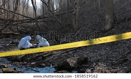 Detectives are collecting evidence in a crime scene. Forensic specialists are making expertise. Police investigation in a forest.