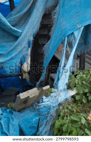 A deteriorated and torn blue tarp
