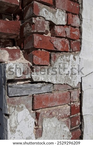 Deteriorating brick column with mortar missing and remnants of stucco