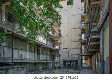 A deteriorating housing complex in Budapest's Hős Street, a symbol of urban poverty and neglect, surrounded by greenery but marked by decay and abandonment. - Powered by Shutterstock