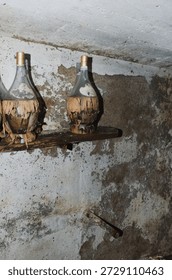 Deteriorating old wine flasks sit on a shelf in an abandoned cellar. Abstract concept: abandonment, neglect, decay, aging, deterioration, passing time, lost hopes, shattered dreams.