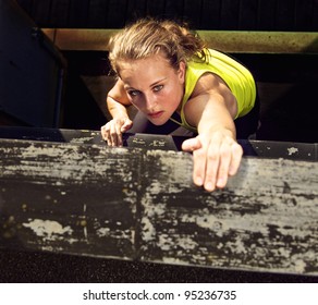 Determination on the face of a traceur climbing the wall of a high industrial building while demonstrating parkour - Powered by Shutterstock