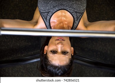 Determined Active Female Athlete Pushing Bench Press Bar Perspective From Above