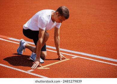 A determined athlete is in a crouched position at the starting line of a red track, prepared to start a sprint race - Powered by Shutterstock