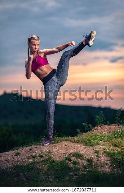 Determined Athletic\
Fitness Woman Doing a High Kick on Hills at Sunset, Mixed Martial\
Arts, MMA, Tae Bo\
Position