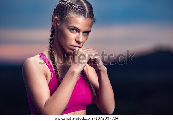 Determined Athletic Fitness Woman in Tae Bo\
Fighting Stance on Hills at\
Sunset