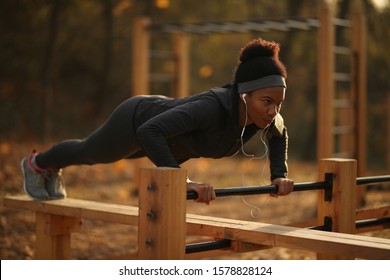 Determined black sportswoman doing push-ups while exercising in the park.  - Powered by Shutterstock