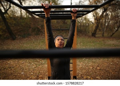 Determined Black Sportswoman Exercising On Brachiation Ladder At Outdoor Gym In The Park. 