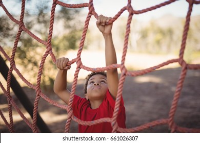 Determined boy climbing a net during obstacle course in boot camp - Powered by Shutterstock