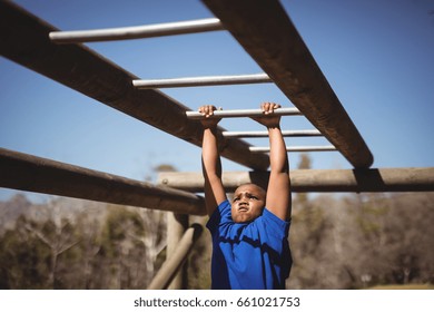 Determined boy exercising on monkey bar during obstacle course in boot camp - Powered by Shutterstock