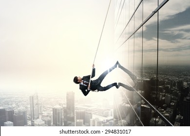 Determined businessman climbing building with help of rope - Powered by Shutterstock