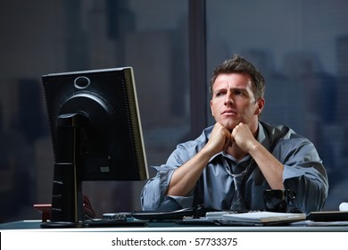 Determined Businessman Concentrating Hard On Difficult Computer Task Working Late In Office Looking Worried.?