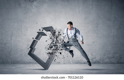 Determined businessman jumping and breaking with kick house concrete figure