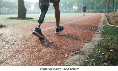 Determined Disabled Athlete Running Outside With Prosthetic Leg. Motivational Amputee On Runner Track