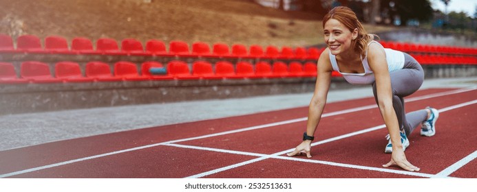 A determined female athlete crouches at the starting line on a race track, ready to sprint. Her expression embodies focus and dedication, with bright red stadium seats in the background. - Powered by Shutterstock