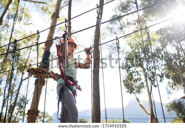 Determined girl\
crossing zip line on a sunny\
day