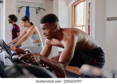 Determined Group Of Multiracial Young Adults On Exercise Bike At The Gym