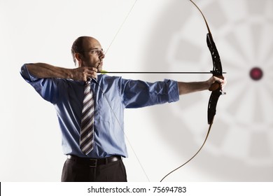 Determined handsome businessman aiming at target with bow and arrow, isolated on white background. - Powered by Shutterstock