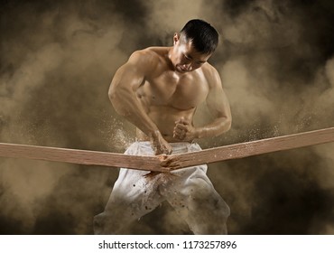 Determined Karate Man Breaking With Hand Wooden Board