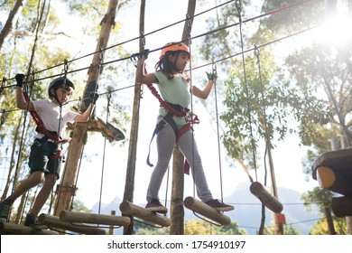 Determined kids crossing zip line on a sunny day - Powered by Shutterstock