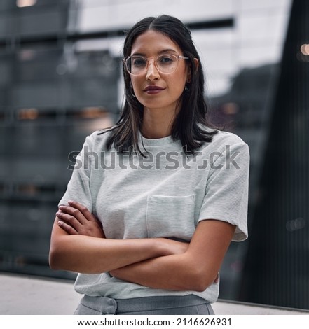 Determined to make it no matter the cost. Shot of an attractive young businesswoman standing alone in the office with her arms folded during a late shift. Foto stock © 