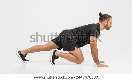 Determined man in a black outfit performing push-ups with an emphasis on form and strength over a clear background