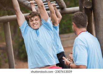 Determined man crossing monkey bars on boot camp obstacle course - Powered by Shutterstock