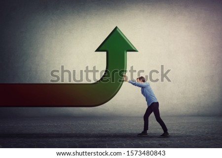 Determined man pushing an arrow to change the direction, bent trajectory to go up. Business purpose achieving success. Raising graph, progress and growth concept. Different thinking, alternative idea.