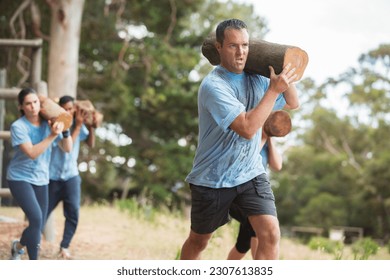 Determined man running with log on boot camp obstacle course - Powered by Shutterstock