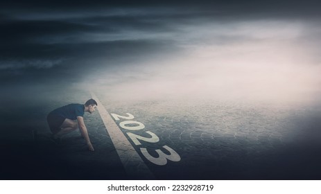 Determined man stands ready in running position at the starting line, looking ahead confident. Guy sprinter begins the new 2023 year challenges. Competitive winner behaviour and motivation concept - Shutterstock ID 2232928719