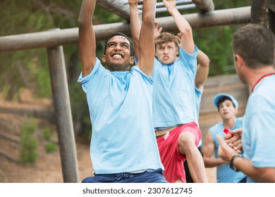 Determined men swinging on monkey bars on boot camp obstacle course - Powered by Shutterstock