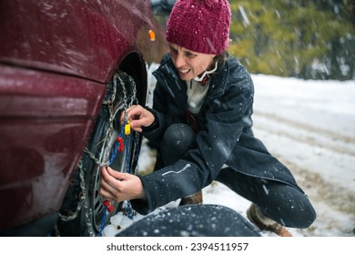 Determined Mid Adult Woman Close-Up, Facing Cold Weather Challenges while Installing Tire Chains for Covered in Snow Slippery Roads - Powered by Shutterstock