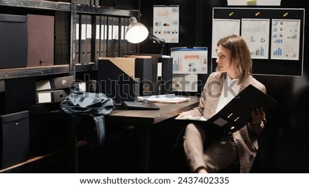 Determined private detective grabs files from shelves to conduct thorough investigation. Caucasian female agent with laptop and research papers, analyzes evidence and gathers information. Tripod shot.