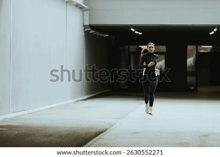 A determined runner navigates an empty urban corridor, focusing on fitness and the rhythm of her pace in a calm morning atmosphere.