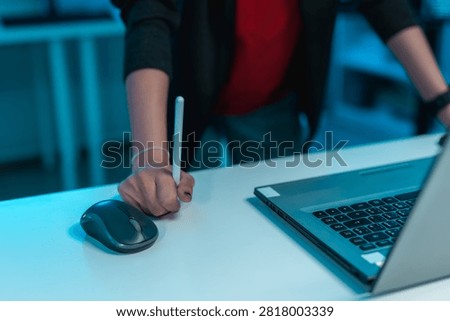 Determined software developer gripping a digital pen beside laptop while solving complex coding challenges, representing problem solving, programming, innovation and productivity.