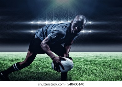 Determined sportsman looking away while playing rugby against spotlights and copy space 3d - Powered by Shutterstock