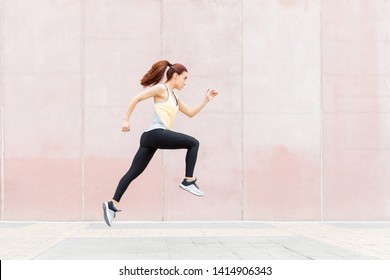 Determined sporty woman in jogging by building in city