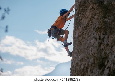 A determined and strong boy climber climbs a steep mountain wall. A child overcomes a difficult route. Extreme sports and rock climbing. - Powered by Shutterstock