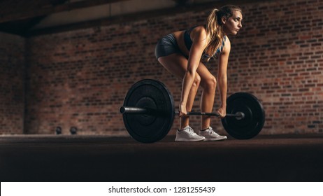 Determined And Strong Fitness Woman Training With Heavy Weights In Fitness Club. Female Athlete Doing Weight Lifting Exercise In Gym.