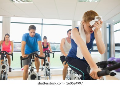 Determined And Tired People Working Out At An Exercise Bike Class In Gym