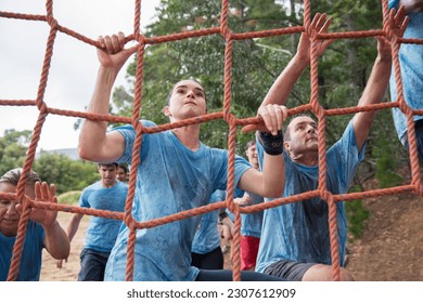 Determined woman climbing net at boot camp obstacle course - Powered by Shutterstock