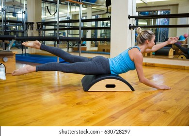 Determined woman exercising on arc barrel in gym - Powered by Shutterstock