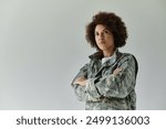 A determined young African American soldier stands proudly, arms crossed, showcasing her military spirit.