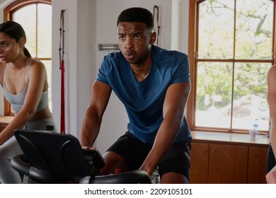 Determined Young Black Man And Biracial Woman Doing Cardio Exercise Bike At The Gym