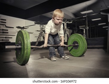 Determined Young Boy Trying To Lift A Heavy Weight Bar