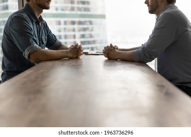Determined young businessmen sit opposite at desk face each other talk speak at business meeting or negotiations. Male rivals or opponents have briefing in office. Rivalry, confrontation concept. - Shutterstock ID 1963736296