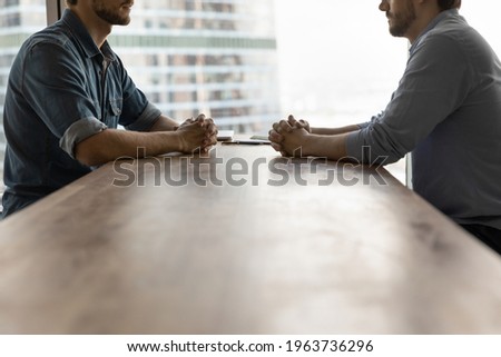 Determined young businessmen sit opposite at desk face each other talk speak at business meeting or negotiations. Male rivals or opponents have briefing in office. Rivalry, confrontation concept. Stock photo © 